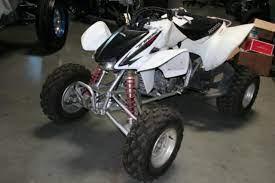 White used ATV with large off-road tires parked indoors, ideal for beginners and adult riders.