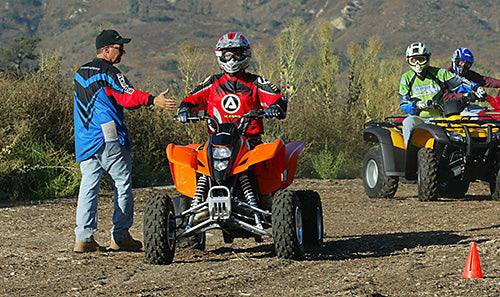ATV safety training outdoors with instructor and youth riders wearing helmets