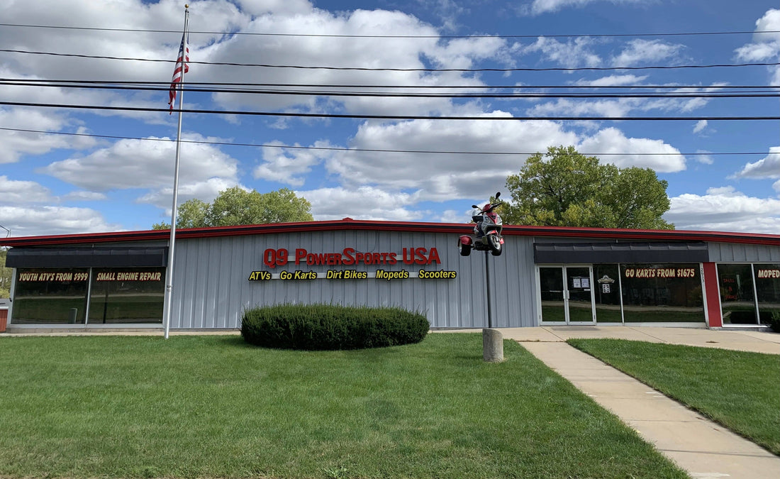 Exterior of a dealership with ATVs, go-karts, dirt bikes, mopeds, and scooters signage, scooter display on pole