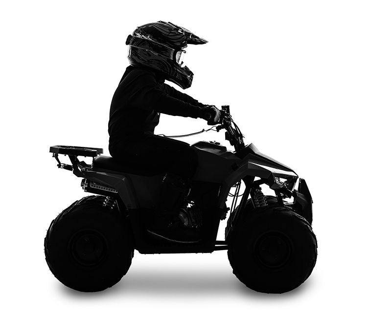 Silhouette of a young rider on an ATV quad bike wearing a helmet, side view
