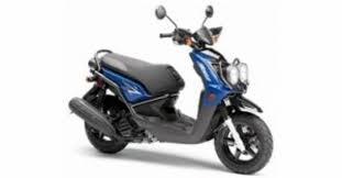 Blue Yamaha Zuma scooter with dual headlights, black seat, side view on white background